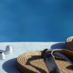 Headphones and sandals by the side of a pool