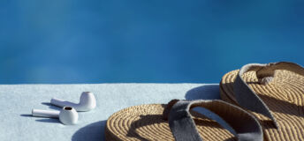 Headphones and sandals by the side of a pool