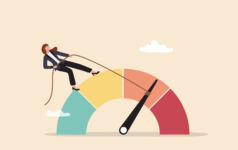 A person standing on a coloured semicircle dial representing risk is pulling a rope attached to the dial towards the green safe side of the spectrum