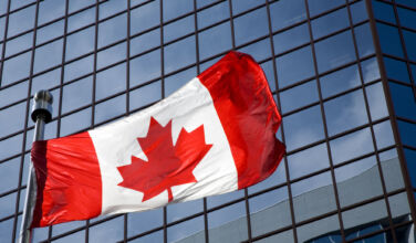 Canadian flag in front of modern building.