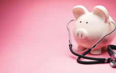 This is a photo of a large white piggy bank on a pink background. This is a concept photo related to finance and the medical hospital industry,