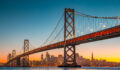 Classic panoramic view of San Francisco skyline with famous Oakland Bay Bridge illuminated in beautiful golden evening light at sunset in summer, San Francisco Bay Area, California, USA