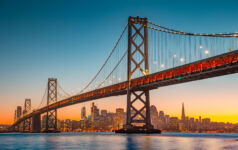 Classic panoramic view of San Francisco skyline with famous Oakland Bay Bridge illuminated in beautiful golden evening light at sunset in summer, San Francisco Bay Area, California, USA