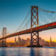 Classic panoramic view of San Francisco skyline with famous Oakland Bay Bridge illuminated in beautiful golden evening light at sunset in summer, San Francisco Bay Area, California, USA