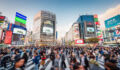 Panorama Shot of People crossing the crowded famous Shibuya Crossing in Downtown Tokyo, illuminated Shibuya Buildings with billboards in the background. Twilight light, close to sunset. Shibuya Crossing, Shibuya Ward, Tokyo, Japan, Asia.