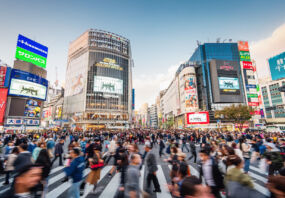 Panorama Shot of People crossing the crowded famous Shibuya Crossing in Downtown Tokyo, illuminated Shibuya Buildings with billboards in the background. Twilight light, close to sunset. Shibuya Crossing, Shibuya Ward, Tokyo, Japan, Asia.