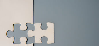 Berkshire Global Advisors: New and returning buyers bolster M&A recovery Two puzzle pieces connecting, one white and one grey, on a contrasting background, symbolizing unity, connection, and collaboration. Copy space for text.