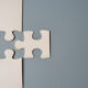 Berkshire Global Advisors: New and returning buyers bolster M&A recovery Two puzzle pieces connecting, one white and one grey, on a contrasting background, symbolizing unity, connection, and collaboration. Copy space for text.