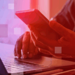 How tech could drive the next wave of democratisation A person is reading their phone while sitting in front of a laptop