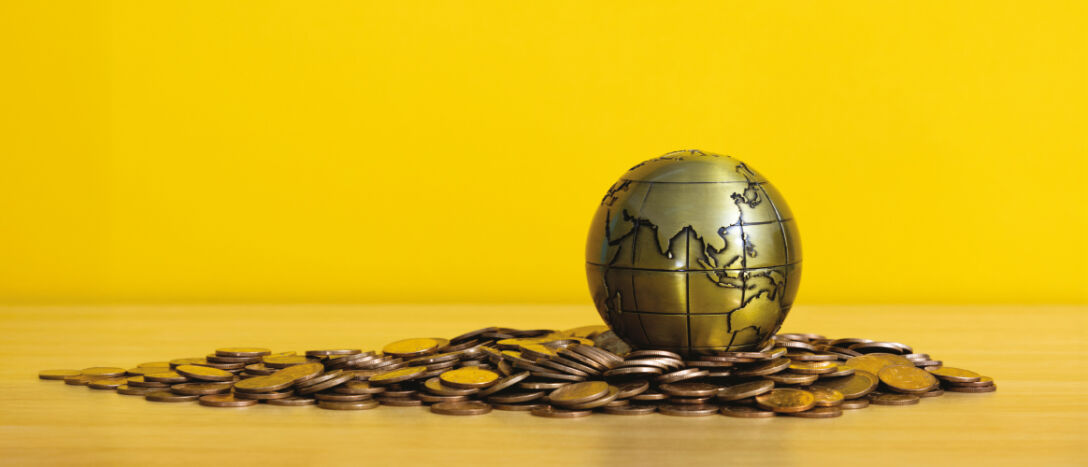 Gold globe with Asia showing laying on gold coins.