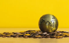 Gold globe with Asia showing laying on gold coins.