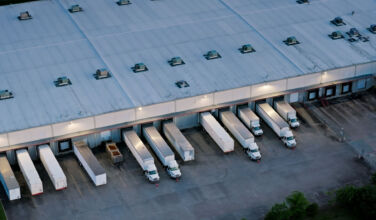 Aerial shot of large semi-trucks parked in a warehouse in Houston, Texas in the evening.