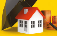 Image of a house under an umbrella next to coins.