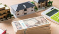 LaSalle Investment Management: Discipline replaces tailwinds in Japan’s real estate market A photo of a desk with a calculator, model homes and a stack of yen bills.