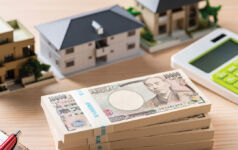 LaSalle Investment Management: Discipline replaces tailwinds in Japan’s real estate market A photo of a desk with a calculator, model homes and a stack of yen bills.