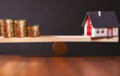 American Landmark Apartments on navigating residential real estate disruptions Image of a house and coins balancing on opposite ends of a wooden scale.