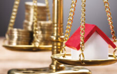 Image of scales balancing coins and a house.
