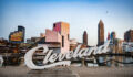 In Ohio the Cleveland script sign is placed in front of the cityscape with the Rock and Roll Hall of Fame building.